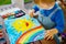 Little toddler girl painting rainbow and sun with water colors during pandemic coronavirus quarantine disease. Children