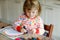 Little toddler girl painting rainbows with crayon colors during pandemic coronavirus quarantine disease. Children paint