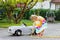 Little toddler girl playing with big vintage toy car and having fun outdoors in summer. Cute child refuel car with water