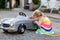 Little toddler girl playing with big vintage toy car and having fun outdoors in summer. Cute child refuel car with water