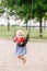 Little toddler girl swinging on swings at playground outside on summer day