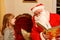 Little toddler girl talking to Santa Claus called Nikolaus or Weihnachtsmann in German. Happy smiling kid waiting for