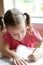 Little toddler girl writing at school desk