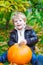 Little toddler kid boy with big orange pumpkin in autumn garden. cute child in fashion clothes having fun with huge