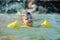 Little toddler kid swimming in lake with inflatable arms aids support