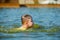 little toddler kid swimming in lake with inflatable arms aids support