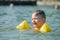 little toddler kid swimming in lake with inflatable arms aids support