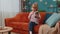Little toddler school kid girl taking selfie photo with smartphone while sitting on sofa at home