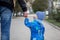 Little toddler on a walk with father, holding dad`s hand a having turned to him, asking something