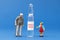 Little toy men made of plastic and an ampoule with a vaccine on a blue background