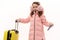 Little traveler girl in pink fluffy earmuffs and down coat, posing with suitcase and boarding pass over white background