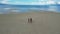 Little triplet sisters running along a sandy beach