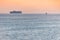 Little tugboat and big cargo ship. Beautiful sunset over sea. Breathtaking travel view, copy space