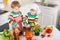 Little twins cooking italian soup and meal with fresh vegetables