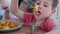 Little twins eats fork fried chicken nuggets with sauce, Boy and girl are having an appetizing dinner in restaurant