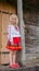 Little ukrainian girl standing near old national wooden house