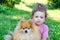 Little upset girl hugging a dog outdoors. unhappy beautiful baby and pomeranian spitz in nature closeup. sad child and