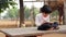 Little village girl doing homework in notebook and sitting on stone near goat farm. Indian countryside footage