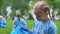 Little volunteer girl collecting rubbish in park, smiling on camera, nature care