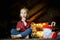 Little white blonde girl sitting on a wooden table in the living room of the Chalet, decorated for Christmas tree and garlands wit
