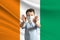 Little white boy in a protective mask on the background of the flag of Cote d`Ivoire Makes a stop sign with his hands, stay at