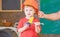 Little worker helping daddy in workshop. Kid playing with toy handsaw and spanner. Father holding protective helmet on