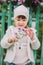 Little young girl sniffs a flower. on a background of green fe