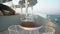 Live camera moves forward along coffee tables in outdoor cafe with blue Mediterranean sea at background. Luxurious