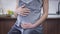 Live camera moves up from high-heels on feet to face of happy confident pregnant woman stroking belly sitting in kitchen