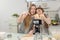 With a live digital camera in the kitchen, mother and daughter smile and have fun while preparing biscuit dough together, daughter
