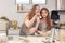 With a live digital camera in the kitchen, mother and daughter smile and have fun while preparing biscuit dough together, daughter