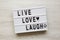 `Live Love Laugh` words on lightbox over white wooden background, top view. Flat lay, overhead, from above