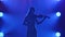 Live performance of a classical melody on the violin. Silhouette of a woman in the smoke on a blue background of