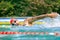 Live portrait of young sportive man, professional swimmer in goggles training at public swimming-pool, outdoors. Sport