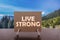 Live strong text on card on the table with mountain valley background