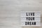 `Live your dream` words on a modern board on a white wooden background, top view. Overhead, from above, flat lay. Copy space