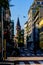 The lively city street at the end of which you can see the tower of the ancient church. Italy