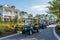 A lively group of people happily riding carts down a bustling street, Golf carts driving through an upscale retirement community,