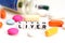 Liver problems concept with close-up of colorful pills and liver word on white background