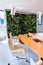 Living green wall, vertical garden indoors with flowers and plants under artificial lighting in meeting boardroom