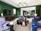 Living room in art deco style with green walls and purple upholstered furniture and cabinets with a TV unit