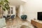 Living room with blue velvet chairs and armchairs, round marble table, fruit bowl and leaded windows, root wood sideboard and