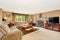 Living room in creamy tones with corner sofa and brick fireplace