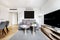 Living room and dining room with gray sofa, large tv on wooden sideboard,