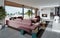 Living room with a large pink sofa and a TV unit with shelves and decor. Living room studio with kitchen and living area. Large