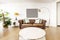 Living room with round white side table, brown leather chesterfield