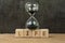 Living time for human life countdown, lifetime or retirement concept, sandglass or hourglass on wooden cube block with alphabet