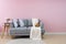 Livingroom interior with grey velvet sofa on pink wall background