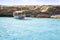 a llaut, typical balearic boat, anchored in a cove of menorca with turquoise crystal clear waters, with a stone wall in the