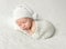 Llitle baby in white knitted hat and suit sleeping